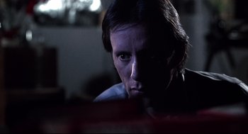 Movie still from “Videodrome” (1983), directed by David Cronenberg – A woman sitting in a dark room with her eyes wide open; Close Up shot, Low angle