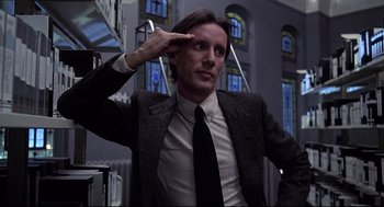 Movie still from “Videodrome” (1983), directed by David Cronenberg – A man in a suit and tie saluting with one hand; Close Up shot, Low angle