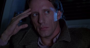 Movie still from “Videodrome” (1983), directed by David Cronenberg – A person wearing a jacket; Close Up shot, Over the shoulder angle