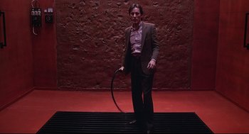 Movie still from “Videodrome” (1983), directed by David Cronenberg – A man in a suit holding a hoop in his hand; Wide shot, Low angle