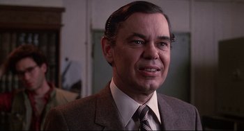 Movie still from “Videodrome” (1983), directed by David Cronenberg – An older man in a suit and tie looking at the camera; Close Up shot, Over the shoulder angle