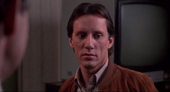 Movie still from “Videodrome” (1983), directed by David Cronenberg – A person wearing a brown jacket; Close Up shot, Low angle