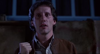 Movie still from “Videodrome” (1983), directed by David Cronenberg – A person wearing a brown jacket; Close Up shot, Low angle