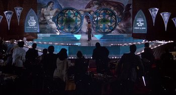 Movie still from “Videodrome” (1983), directed by David Cronenberg – A group of people standing in front of a stage; Extreme Wide shot, High angle