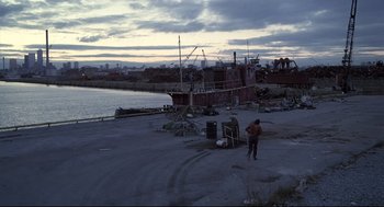Movie still from “Videodrome” (1983), directed by David Cronenberg – A man standing on a beach near a boat; Extreme Wide shot, High angle