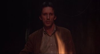 Movie still from “Videodrome” (1983), directed by David Cronenberg – A man in a brown jacket is in the dark; Close Up shot, Low angle