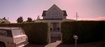 Movie still from “Village of the Damned” (1995), directed by John Carpenter – A house that is surrounded by bushes and trees; Wide shot, Low angle