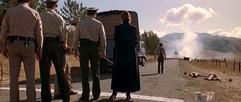 Movie still from “Village of the Damned” (1995), directed by John Carpenter – A woman standing on the side of a road next to a truck; Wide shot, Low angle