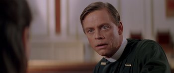 Movie still from “Village of the Damned” (1995), directed by John Carpenter – A person wearing a priest's outfit; Close Up shot, Low angle