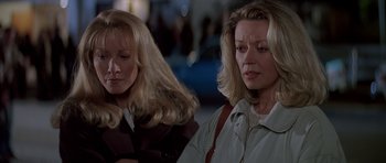 Movie still from “Village of the Damned” (1995), directed by John Carpenter – Two women with blonde hair and one is wearing a brown jacket; Close Up shot, Over the shoulder angle