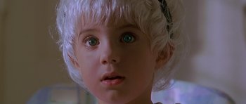 Movie still from “Village of the Damned” (1995), directed by John Carpenter – A child's face in a white wig; Close Up shot, High angle