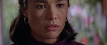 Movie still from “Village of the Damned” (1995), directed by John Carpenter – A woman's face in a purple shirt; Close Up shot, High angle