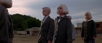 Movie still from “Village of the Damned” (1995), directed by John Carpenter – A couple of people standing next to each other; Medium shot, Low angle