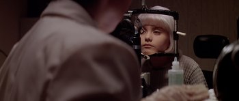 Movie still from “Village of the Damned” (1995), directed by John Carpenter – A woman is looking into a mirror at a person's eyes; Close Up shot, Over the shoulder angle