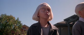 Movie still from “Village of the Damned” (1995), directed by John Carpenter – A woman with white hair blowing a bubble; Close Up shot, Low angle