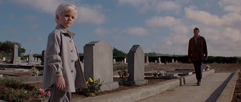 Movie still from “Village of the Damned” (1995), directed by John Carpenter – A woman standing in front of a grave yard; Medium shot, Low angle