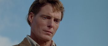 Movie still from “Village of the Damned” (1995), directed by John Carpenter – A man's face with a blue sky background; Close Up shot, Low angle