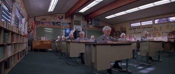 Movie still from “Village of the Damned” (1995), directed by John Carpenter – A group of people sitting at desks in a classroom; Wide shot, High angle