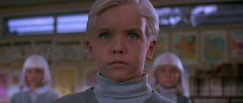 Movie still from “Village of the Damned” (1995), directed by John Carpenter – A young boy with blonde hair and green eyes; Close Up shot, Low angle