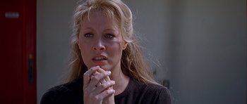 Movie still from “Village of the Damned” (1995), directed by John Carpenter – A woman with long blonde hair is holding her hands to her face; Close Up shot, Over the shoulder angle