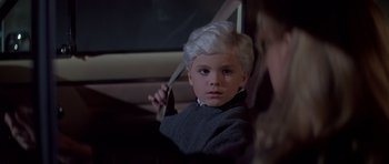 Movie still from “Village of the Damned” (1995), directed by John Carpenter – A young boy sitting in the back seat of a car; Close Up shot, High angle
