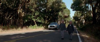 Movie still from “Village of the Damned” (1995), directed by John Carpenter – Two people walking down the street in front of a car; Wide shot, Low angle