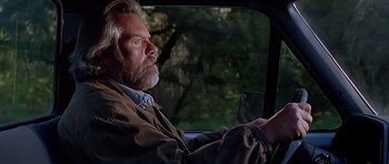 Movie still from “Village of the Damned” (1995), directed by John Carpenter – An older man sitting in the drivers seat of a car; Close Up shot, Low angle