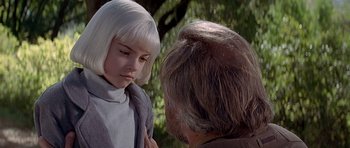 Movie still from “Village of the Damned” (1995), directed by John Carpenter – A young girl and an older man are talking to each other; Close Up shot, Over the shoulder angle