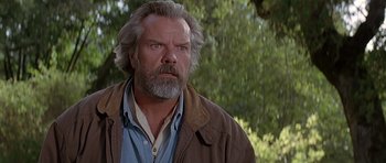 Movie still from “Village of the Damned” (1995), directed by John Carpenter – A man with a beard and a jacket on; Close Up shot, Low angle