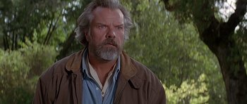 Movie still from “Village of the Damned” (1995), directed by John Carpenter – A man with a beard and a jacket on; Close Up shot, Low angle