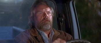 Movie still from “Village of the Damned” (1995), directed by John Carpenter – A man with a beard and a jacket on looking surprised; Close Up shot, Low angle