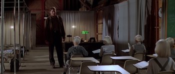 Movie still from “Village of the Damned” (1995), directed by John Carpenter – A man and two women sitting in a classroom; Wide shot, Low angle