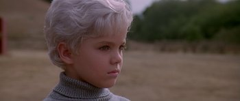 Movie still from “Village of the Damned” (1995), directed by John Carpenter – A young boy with white hair looking to his left; Close Up shot, High angle