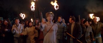 Movie still from “Village of the Damned” (1995), directed by John Carpenter – A group of people holding torches in the dark; Medium shot, Low angle