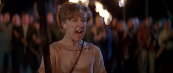 Movie still from “Village of the Damned” (1995), directed by John Carpenter – An older woman with her mouth wide open; Medium shot, Low angle