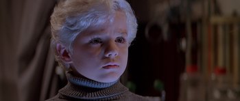 Movie still from “Village of the Damned” (1995), directed by John Carpenter – A young child with a sweater on; Close Up shot, High angle