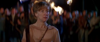 Movie still from “Village of the Damned” (1995), directed by John Carpenter – A person wearing a dress with lights in the background; Close Up shot, Low angle
