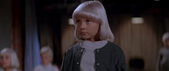 Movie still from “Village of the Damned” (1995), directed by John Carpenter – A young girl with white hair looking to her left; Close Up shot, High angle