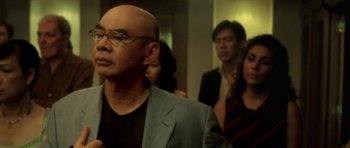 Movie still from “Vinyan” (2008), directed by Fabrice du Welz – A group of people standing in a room; Close Up shot, Over the shoulder angle