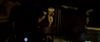 Movie still from “Vinyan” (2008), directed by Fabrice du Welz – A man looking out a window at night; Extreme Close Up shot, Low angle