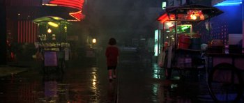 Movie still from “Vinyan” (2008), directed by Fabrice du Welz – A person walking down a wet street at night; Extreme Wide shot, High angle