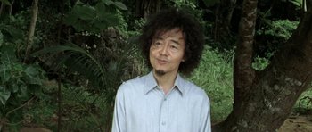 Movie still from “Vinyan” (2008), directed by Fabrice du Welz – A man in a blue dress shirt with a beard; Close Up shot, Low angle