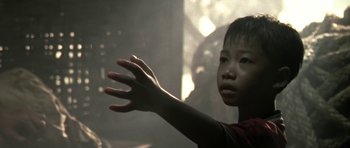 Movie still from “Vinyan” (2008), directed by Fabrice du Welz – A young boy with his arm outstretched in the dark; Close Up shot, Over the shoulder angle