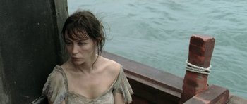 Movie still from “Vinyan” (2008), directed by Fabrice du Welz – A woman sitting on a dock near the water; Close Up shot, High angle