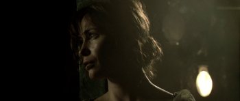 Movie still from “Vinyan” (2008), directed by Fabrice du Welz – A person's face in a dark room; Close Up shot, Over the shoulder angle