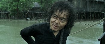 Movie still from “Vinyan” (2008), directed by Fabrice du Welz – A man in a black shirt is standing in the rain; Close Up shot, Low angle