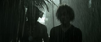 Movie still from “Vinyan” (2008), directed by Fabrice du Welz – Two people standing in the rain under an umbrella; Close Up shot, Low angle