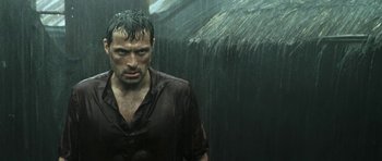 Movie still from “Vinyan” (2008), directed by Fabrice du Welz – A man standing in the middle of a rain storm; Medium shot, Over the shoulder angle