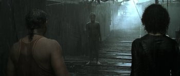 Movie still from “Vinyan” (2008), directed by Fabrice du Welz – A boy standing in the middle of a wooden walkway; Wide shot, Over the shoulder angle