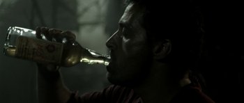 Movie still from “Vinyan” (2008), directed by Fabrice du Welz – A man is drinking a beer from a bottle; Close Up shot, High angle